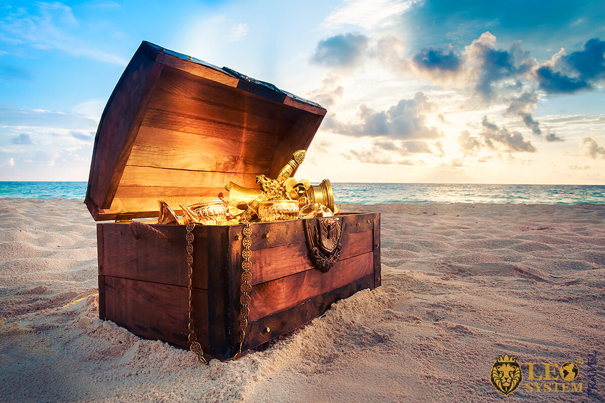 Image of a wooden chest with gold ornaments lying on the sand